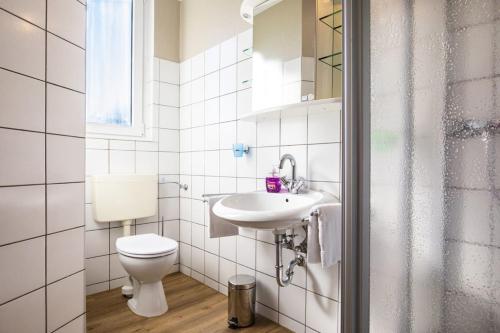 a white bathroom with a toilet and a sink at Wohnung Nr 2 im Wikingerhof in Altfunnixsiel