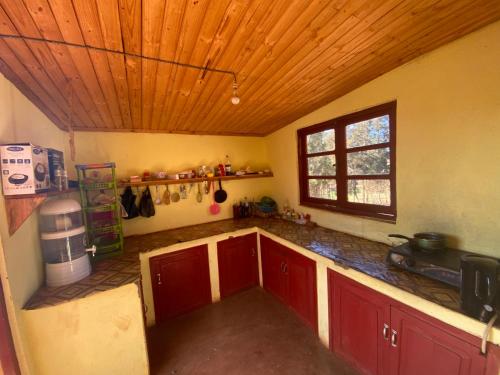 Il comprend une cuisine avec des placards rouges et un plafond en bois. dans l'établissement Chambres d'hôtes du lycée Picot de Clorivière dont les revenus financent l'éducation des élèves, à Antsirabe