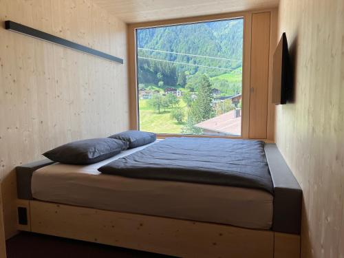 a bed in a room with a large window at Revier Mountain Lodge Montafon in Sankt Gallenkirch