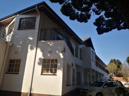 a white house with a car parked in front of it at CHIC Guest House & Solar system accommodations in Germiston