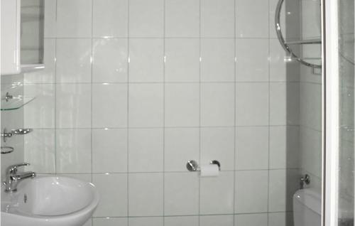 a white tiled bathroom with a sink and a shower at Nice Apartment In Kopalino With Wifi in Kopalino