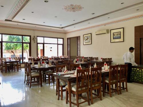 a restaurant with tables and chairs and a man standing in a room at The Birder's Inn in Bharatpur