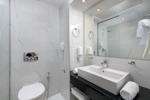 a white bathroom with a sink and a mirror at Oceanis Beach Hotel in Ixia