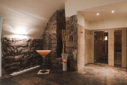 un corridoio con un muro in pietra e un vaso con fiori di Hotel Mandelhof ***S ad Appiano sulla Strada del Vino