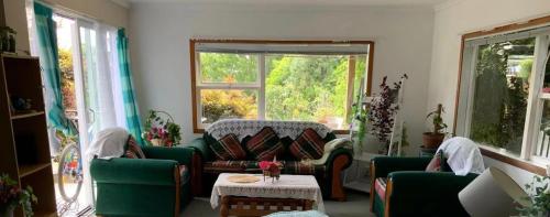 a living room with green furniture and a large window at Slow Time Homestay in Auckland