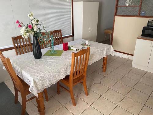 a dining room table with a vase of flowers on it at Slow Time Homestay in Auckland