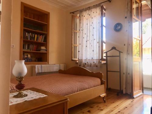 a bedroom with a bed and a table and a window at THEO TRADITIONAL HOUSE in Eptalofos