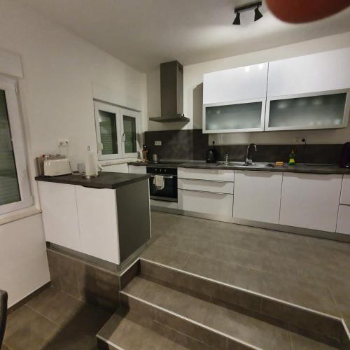 a kitchen with white cabinets and stainless steel appliances at Villa BOTIĆ in Trogir
