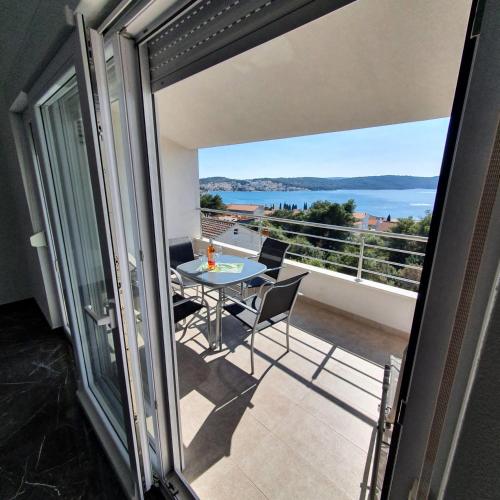 a balcony with a table and chairs and a view of the water at Villa BOTIĆ in Trogir
