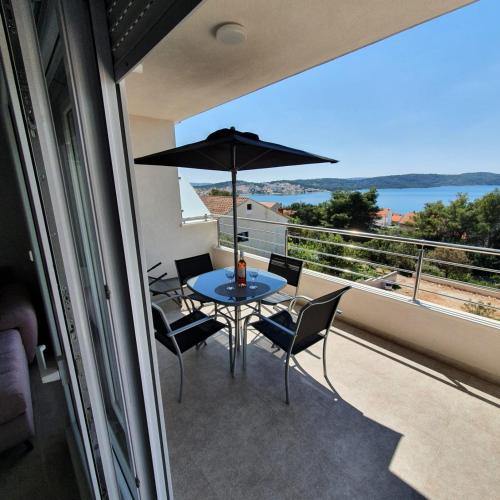 a balcony with a table and chairs and an umbrella at Villa BOTIĆ in Trogir