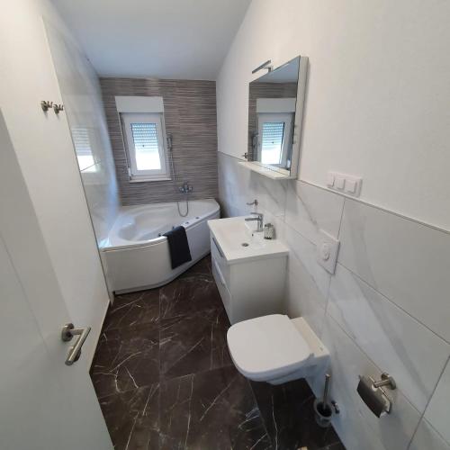 a bathroom with a tub and a toilet and a sink at Villa BOTIĆ in Trogir