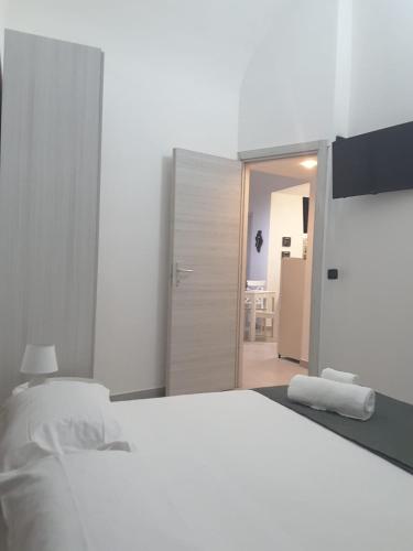a white bedroom with a white bed and a doorway at A casa dei 3 in Catania