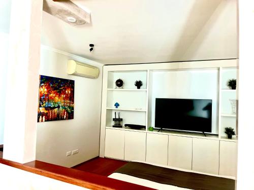 un soggiorno con un grande centro di intrattenimento bianco con TV a schermo piatto di Oderisi Studio Suite a Roma