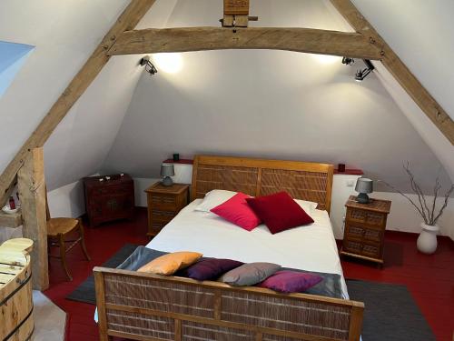 1 dormitorio con 1 cama con almohadas rojas y moradas en chambres d'hôtes et Gîte Le Moulin Sainte Marie, en Estrée-Wamin