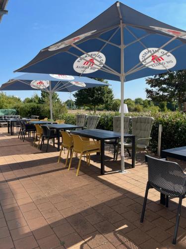 a row of tables and chairs under an umbrella at AiREA Hotel in Büren