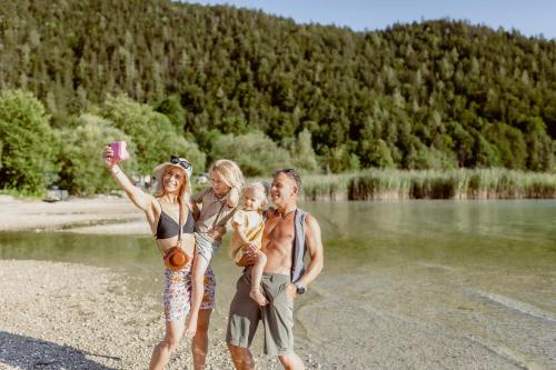 a group of people standing next to a body of water at Seehotel Berau in St. Wolfgang
