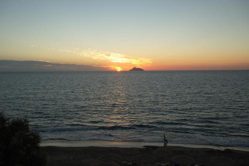 a sunset over the ocean with a island in the distance at ARTEMIS beach studios in Kalamaki Heraklion