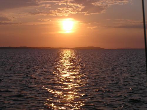 a sunset over the ocean with the sun in the sky at Peeneurlaub in Lassan
