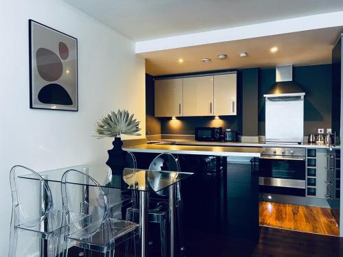 eine Küche mit schwarzen Schränken und einem Glastisch in der Unterkunft 2 Bedroom Penthouse Birmingham in Birmingham