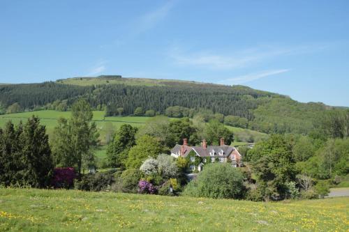 a house in a field with a hill in the background at Milebrook House in Knighton