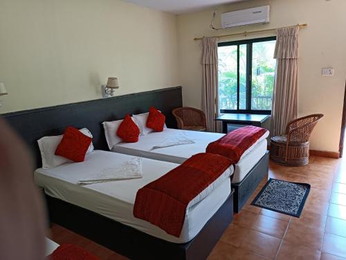 a bedroom with two beds with red pillows at Pokhara Cottage in Pokhara