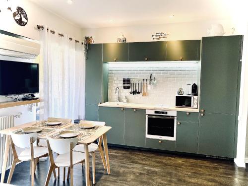 a kitchen with green cabinets and a table with white chairs at Baie-Des-Anges Studio Front de Mer in Villeneuve-Loubet