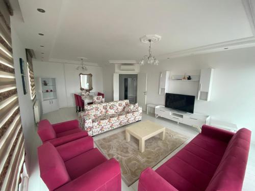 a living room with pink couches and a tv at TRABZON PANORAMA APART in Trabzon