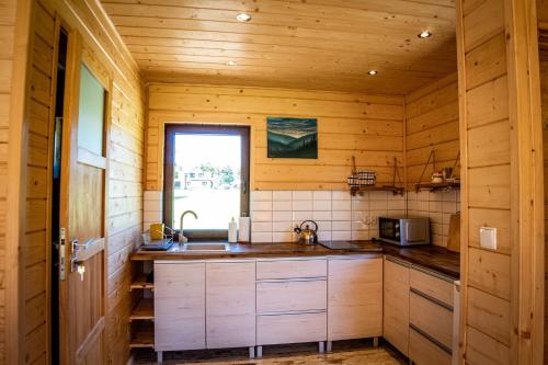 a kitchen with wooden walls and a sink and a window at Domki przy Młynie " Koło Młyńskie " in Krościenko
