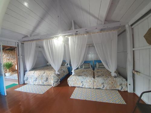 two beds in a room with white curtains at Scuba Republic Beach Bungalows in Bira