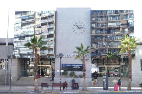 a building with a clock on the side of it with palm trees at Céntrico apartamento en el Riscal in Alicante