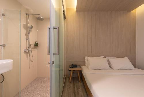 a small bathroom with a bed and a shower at The Period Pratunam in Bangkok