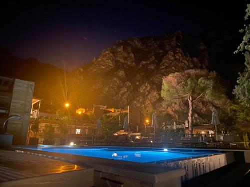 a swimming pool at night with a mountain in the background at Sibenbras Natural Aparthotel in Limone sul Garda