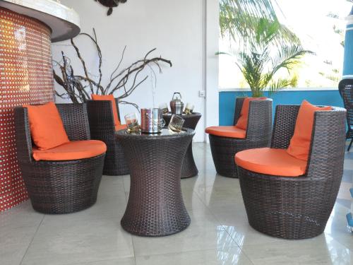 a row of wicker chairs with orange seats in a lobby at 3Ds International Tourist Home in Mahébourg