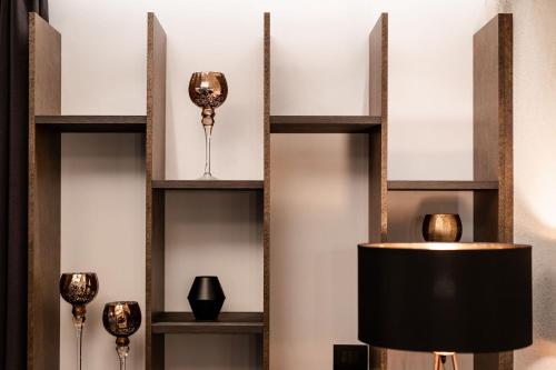 a wall with shelves with vases and a lamp at Sibenbras Natural Aparthotel in Limone sul Garda