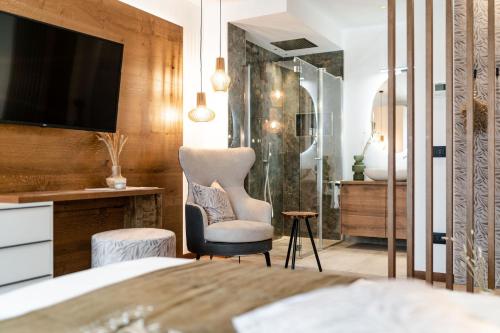 a bedroom with a bed and a chair and a television at Sibenbras Natural Aparthotel in Limone sul Garda