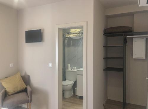 a bathroom with a toilet and a stairwell with a chair at Rua Grande Hotel in Viana do Castelo