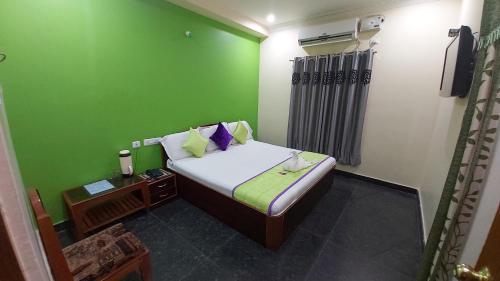 a small room with a bed with a green wall at KSR GRAND in Srikalahasti