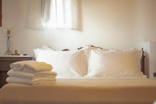 a bed with white pillows and towels on it at Castello di Haria in Kaloú