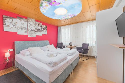 ヘッヒンゲンにあるHotel am Schlossplatzのピンクの壁のベッドルーム1室(大型ベッド1台付)