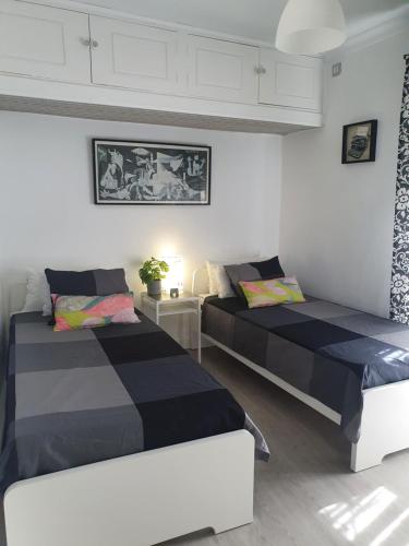 two beds in a room with white and black at NOOL Sevilla in Seville