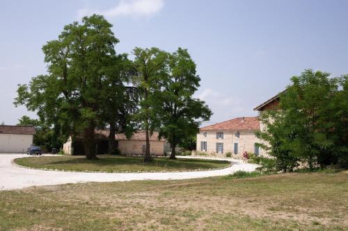 stary dom z drzewem i drogą w obiekcie Le Clos Saint-Jean - Chambre d'hôte Rosie w mieście Saint-Jean-de-Thurac