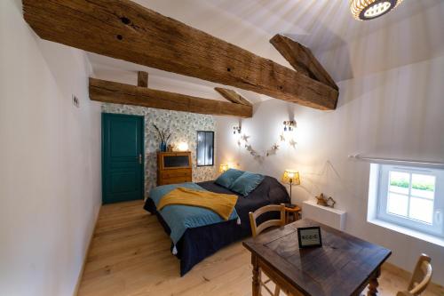 Un dormitorio con una cama y una mesa. en Le Clos Saint-Jean - Chambre d'hôte Rosie, en Saint-Jean-de-Thurac