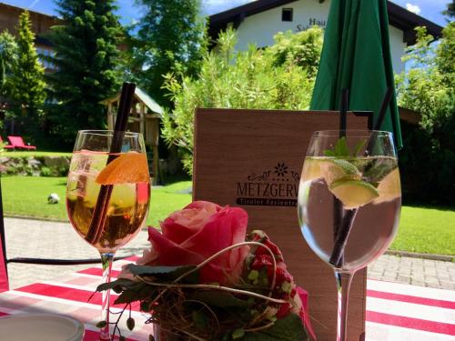 a table with two glasses of wine and a bowl of flowers at Hotel Metzgerwirt in Kirchberg in Tirol