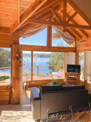 a living room with a couch and a large window at Cabañas Bahiamia in Villa Pehuenia