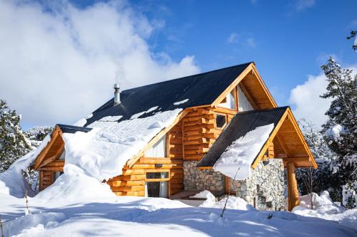 a log cabin in the snow with snow at Cabañas Bahiamia in Villa Pehuenia