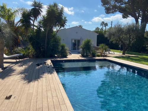 a swimming pool in front of a house with palm trees at Le Mas de la Dame in Saint-Tropez