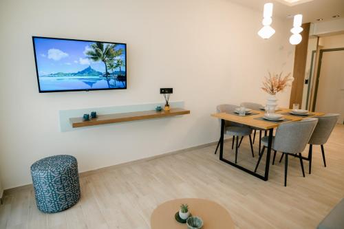 sala de estar con mesa y TV en la pared en Magico Suites City Heart Luxury Appartments, en Alexandroupoli
