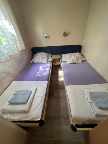 two beds in a room with purple and white sheets at Apartments and bungalows vila Dalibor in Nin