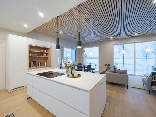 cocina con armarios blancos y sala de estar. en Villa Forest, en Rovaniemi