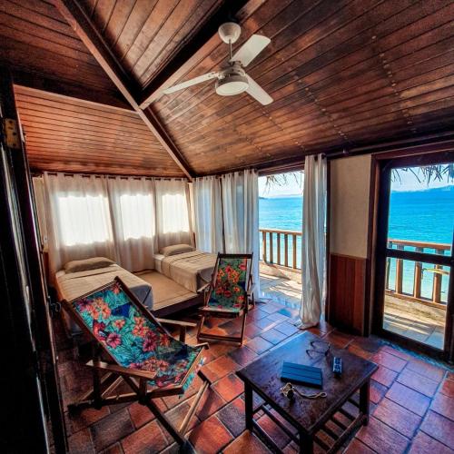 a living room with a couch and chairs and the ocean at Orlanova Hotel in Arraial do Cabo